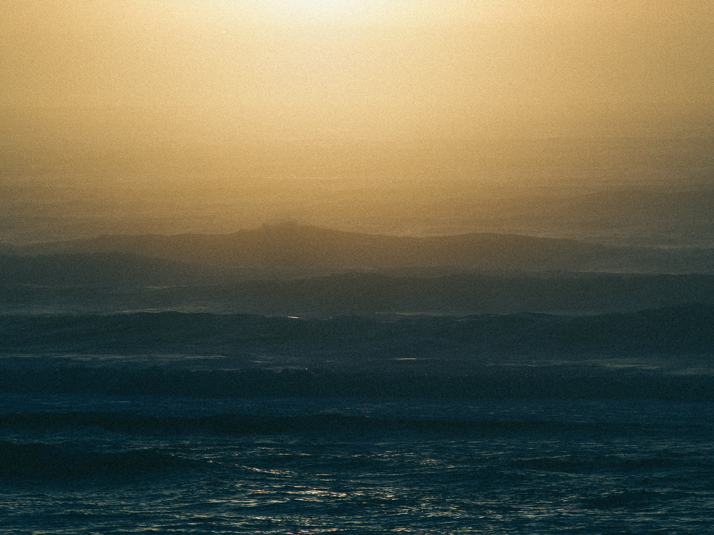 Hazy golden light over distant mountains and water